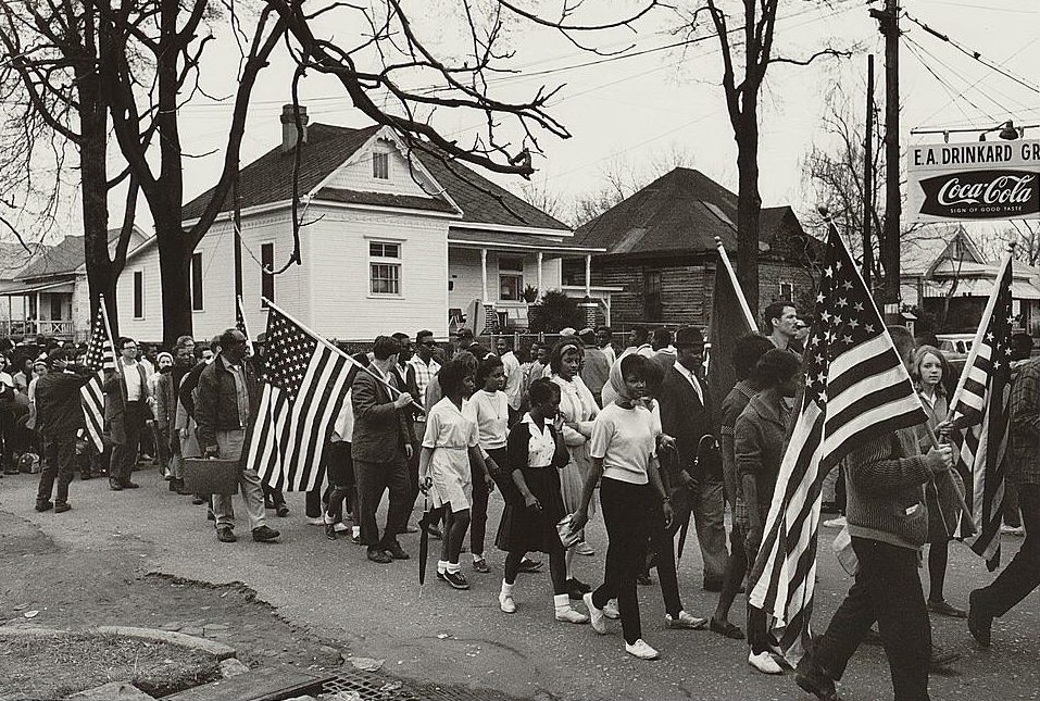 Participants, some carrying American flags, marching in the civil rights march from Selma to Montgomery, Alabama in 1965. Photo by Peter Pettus. Source: Library of Congress.